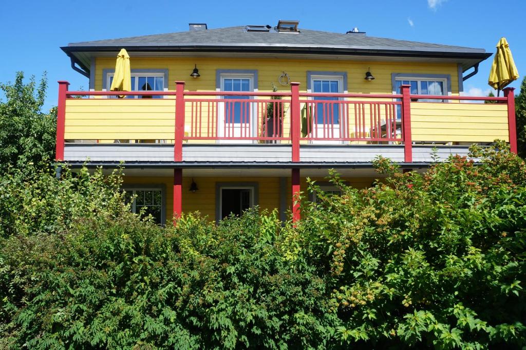 una grande casa gialla con una terrazza in cima agli alberi di Guest House Mr Fox a Druskininkai