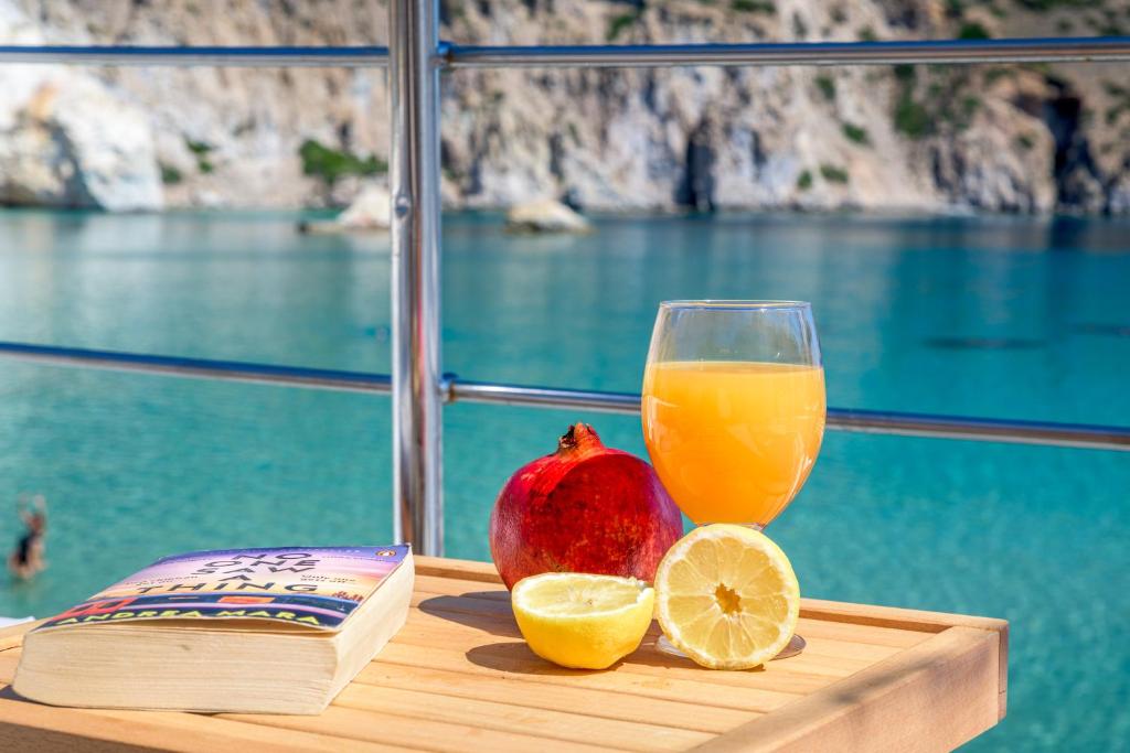 a wooden table with a glass of orange juice and a book at Giasemi Boathouse in Firopótamos