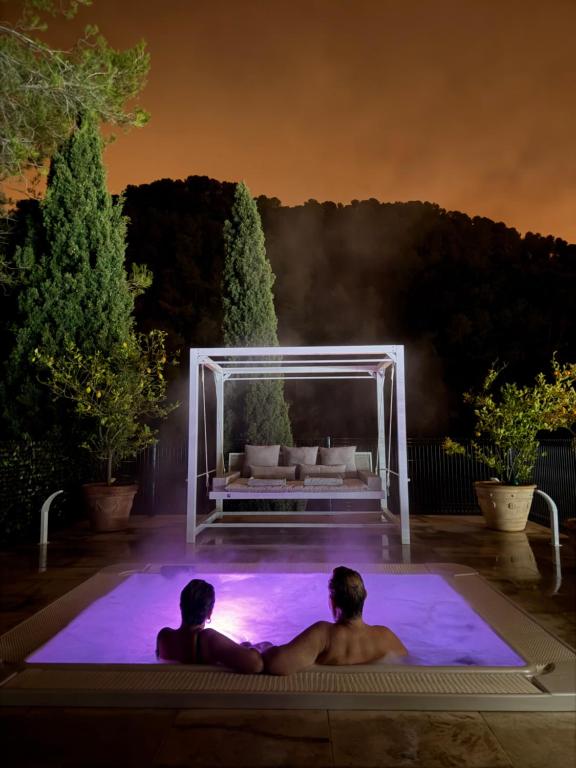 two men sitting in a swimming pool at night at Domaine Baccia Donna Proche Nice, Climatisation, Jacuzzi chauffé, Pétanque & Parking gratuit in La Trinité