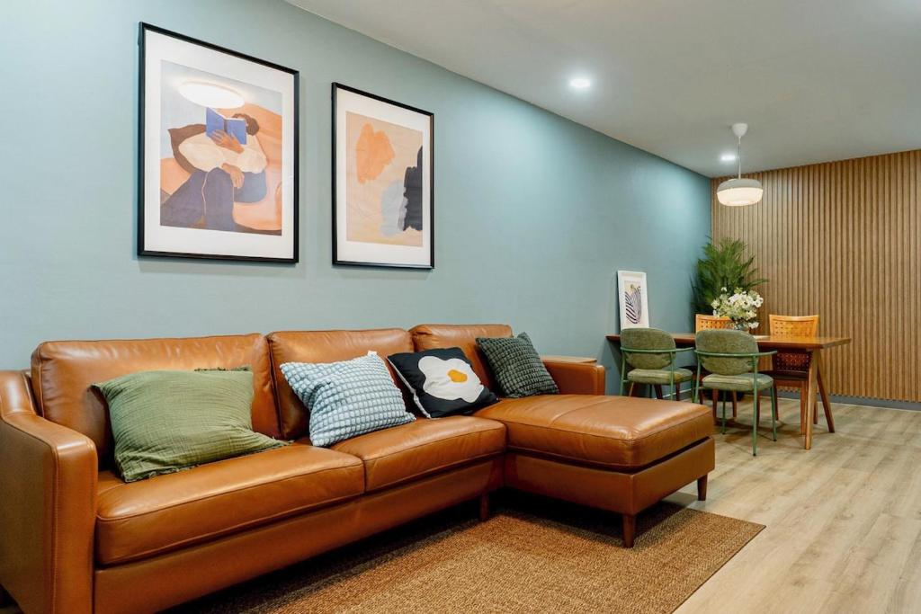 a living room with a brown leather couch and a table at Cozy Nest Ladprao - 3BR Townhome 3min walk from MRT in Bangkok
