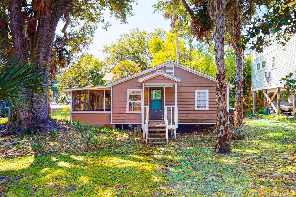 a small red house with a porch in a yard at Cozy Corner in Folly Beach