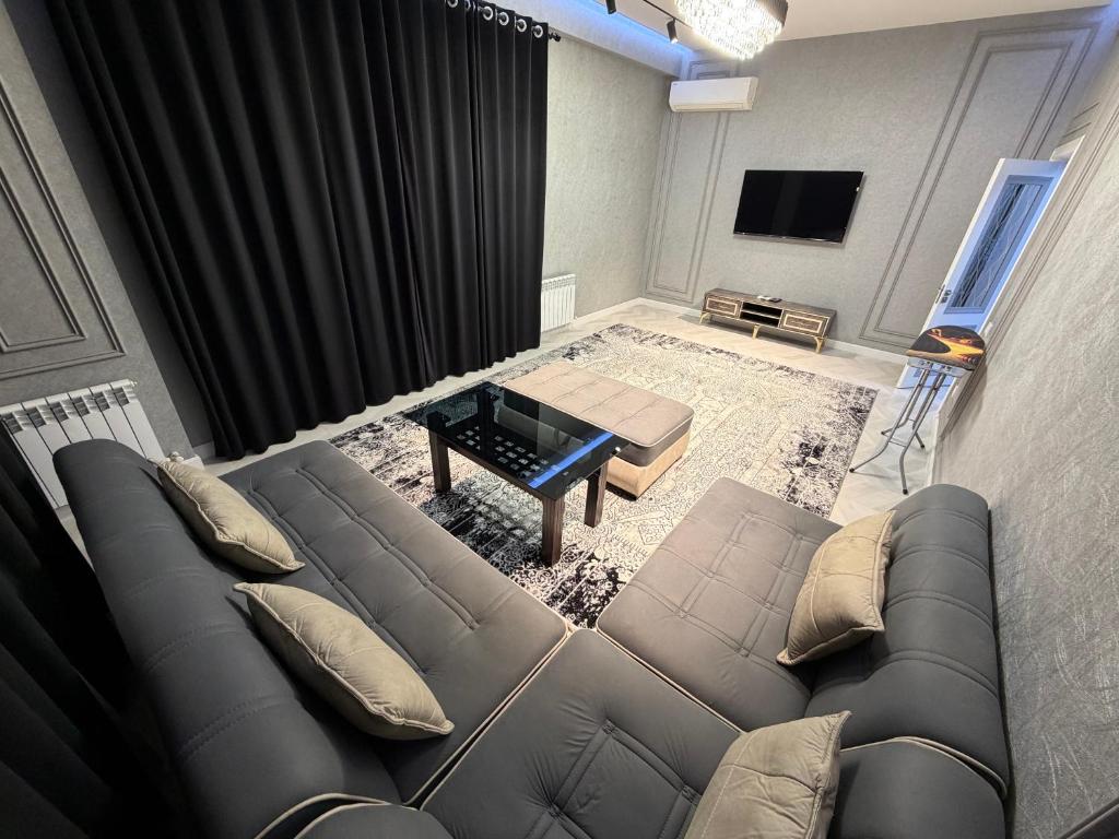 een woonkamer met een bank en een televisie bij Tashkent City Apartments 1A in Tasjkent