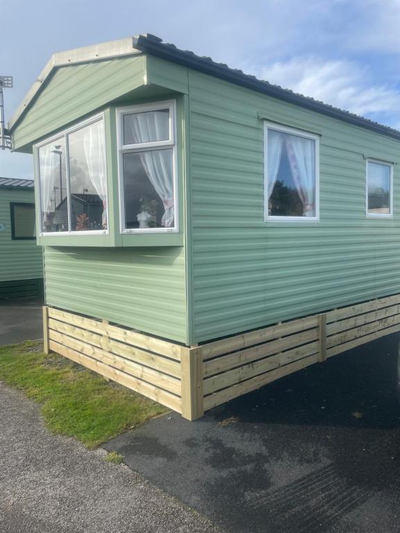 a green tiny house with two windows at Gemini in Heysham