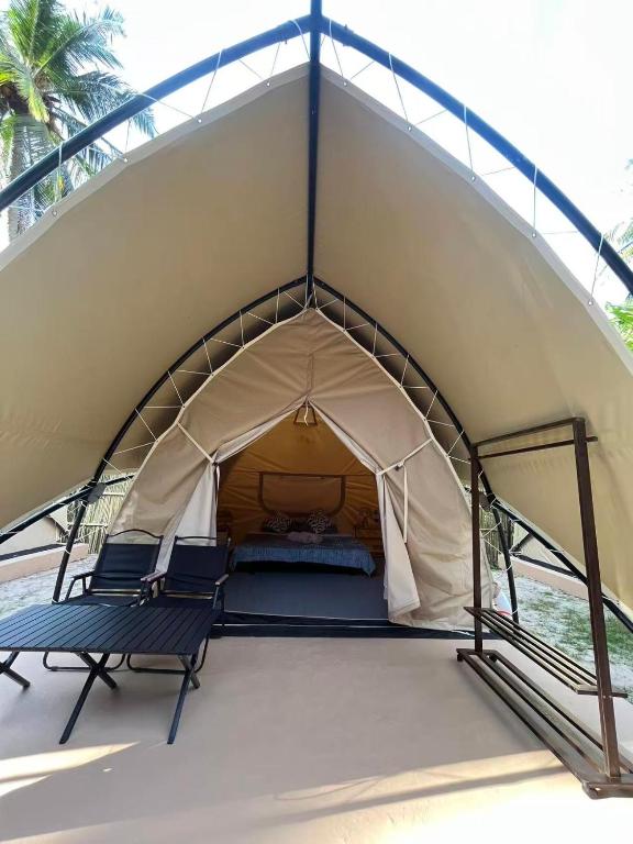 a tent with two chairs and a bed in it at Milky Way Glamping in Busuanga