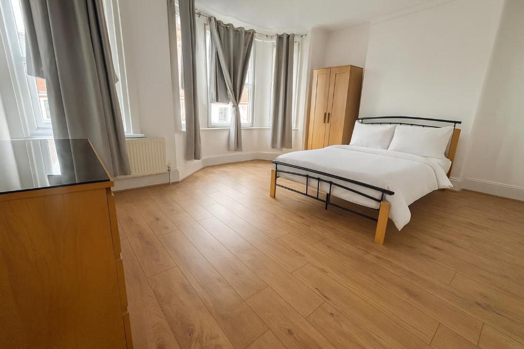 ein weißes Schlafzimmer mit einem Bett und einem Fernseher in der Unterkunft Big Double room wimbledon Park in London