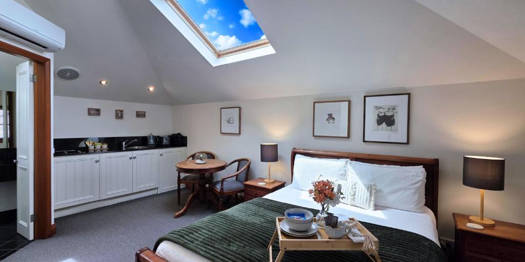 Sandstone Suites - In the heart of Port Fairy في بور فيري: غرفة نوم بسرير وطاولة عليها ورد