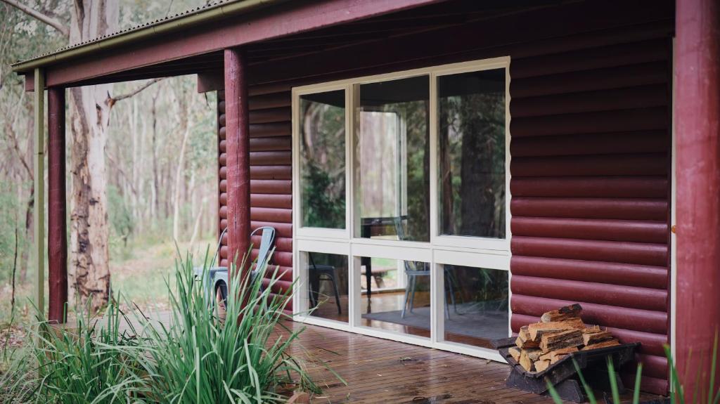 Werriberri في Medlow Bath: شرفة مغطاة بشبكة واقية لمنزل أحمر اللون بها نوافذ