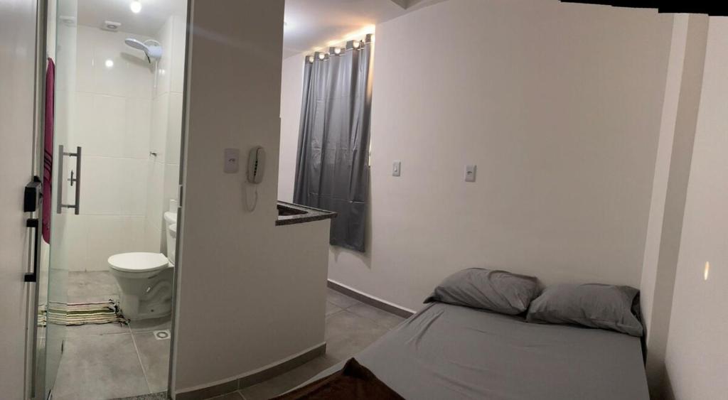 a bedroom with a bed and a bathroom with a shower at Flat 2 ao lado da UFSJ e Igreja São Francisco in São João del Rei