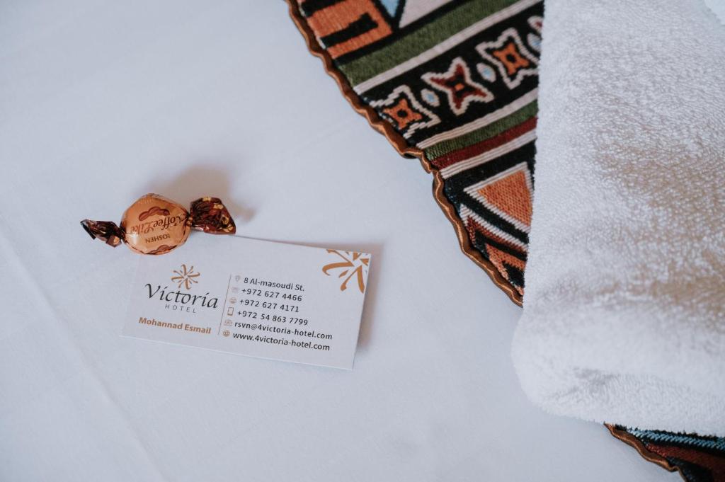 een witte handdoek met een bordje ernaast een stropdas bij Victoria Hotel in Jeruzalem