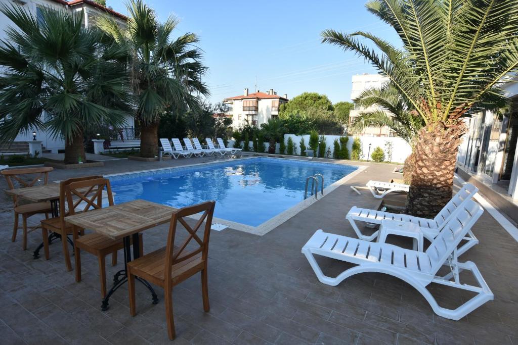 un patio con mesas y sillas junto a una piscina en Uzunhan Hotel, en Ayvalık