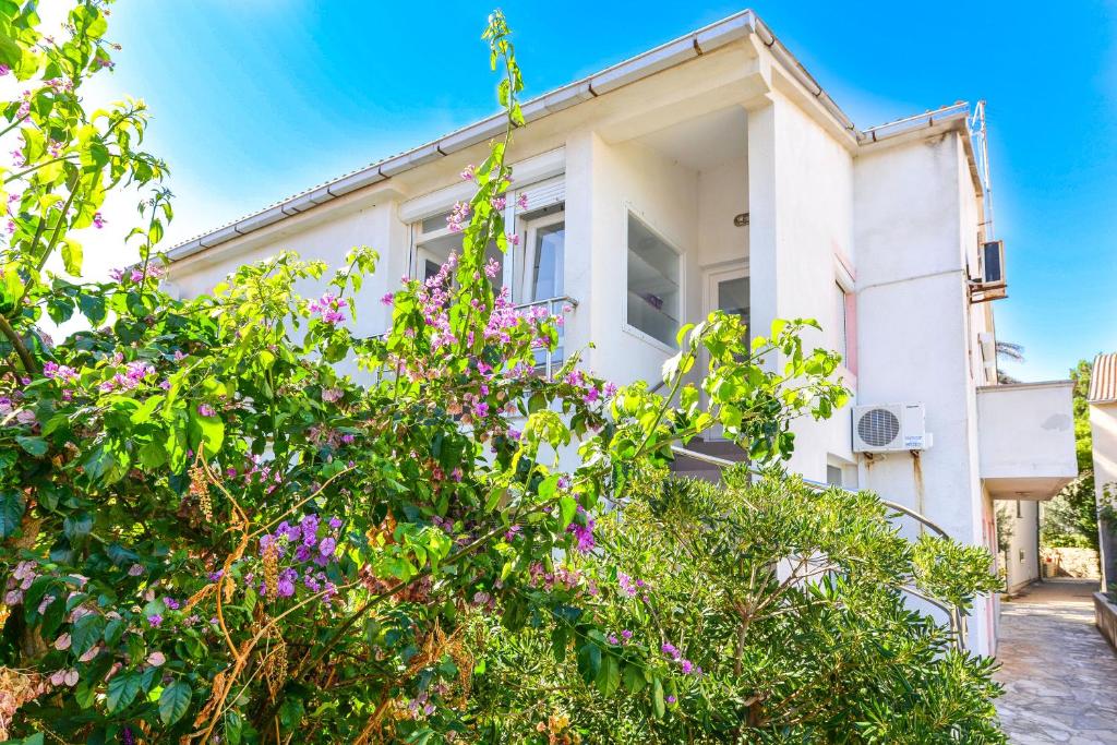 een wit huis met bloemen ervoor bij Apartments Breza in Razvala