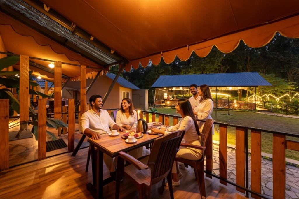 un grupo de personas sentadas en una mesa en una cubierta en Dandeli Vacation, en Dandeli