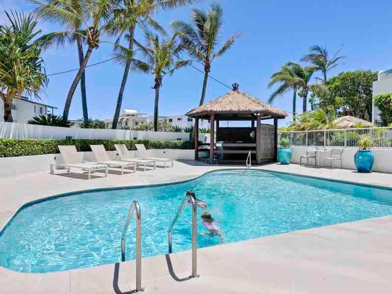 a swimming pool with a gazebo and palm trees at Beach side Cotton Tree Family Friendly Resort in Maroochydore