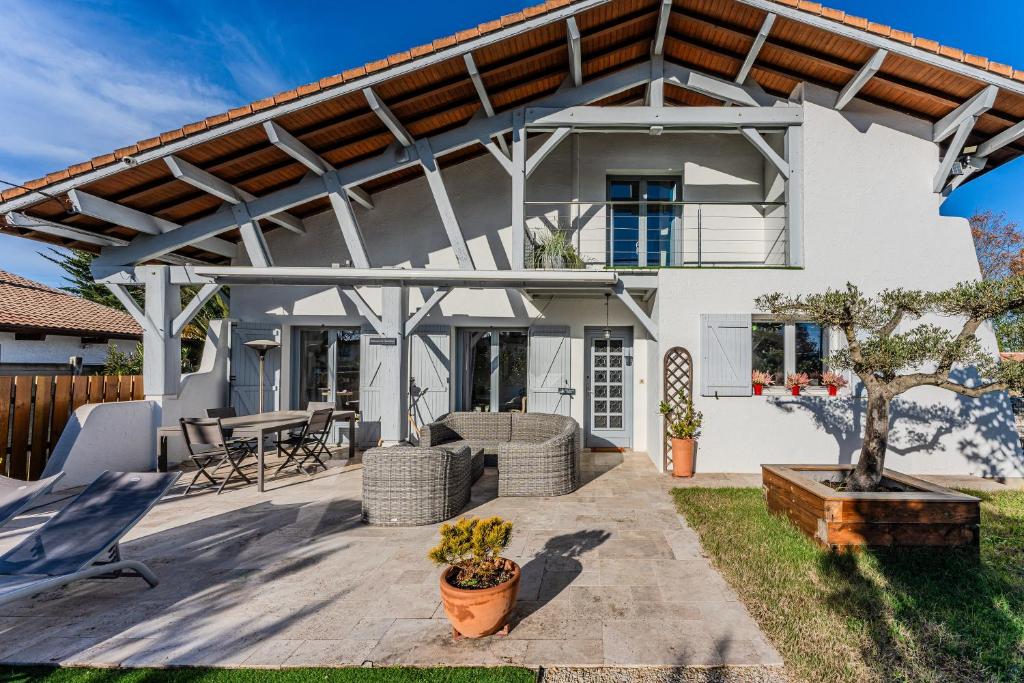 a white house with a pergola on a patio at Chambre D'hote Chez Amaya in Gujan-Mestras