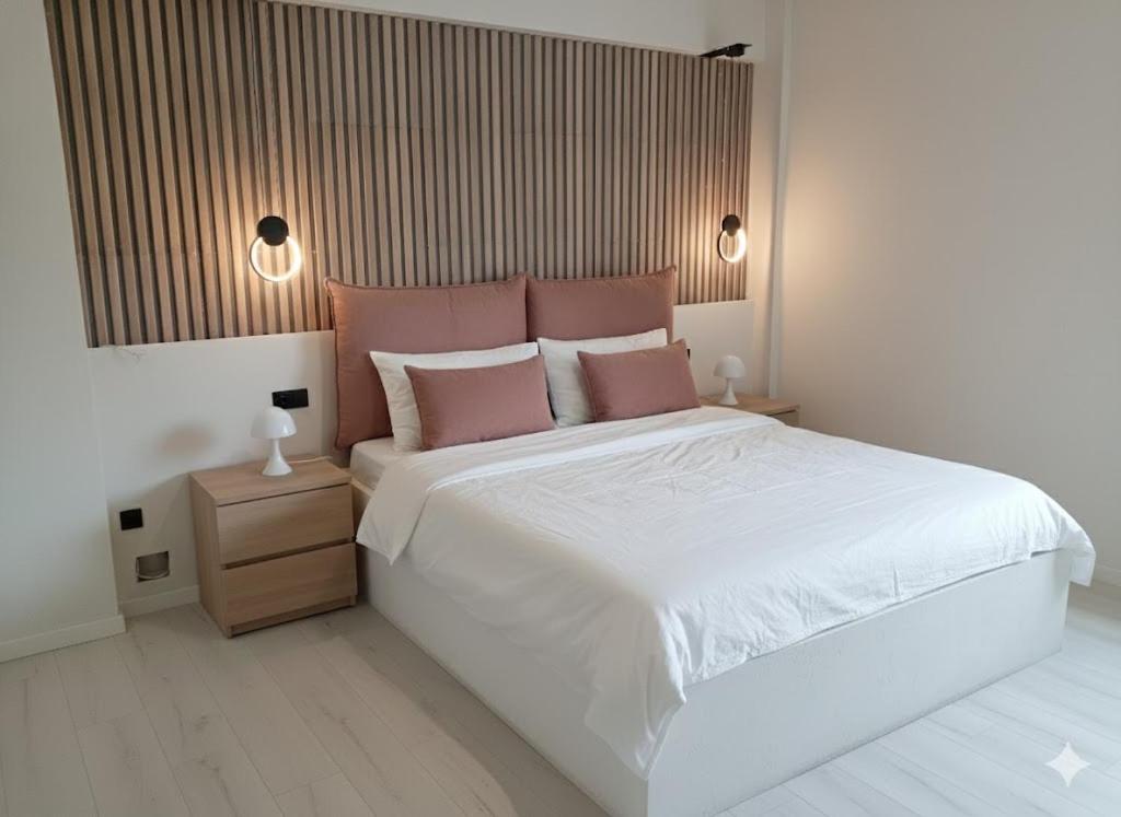 a bedroom with a large white bed with pink pillows at River Palace Suite in Tríkala