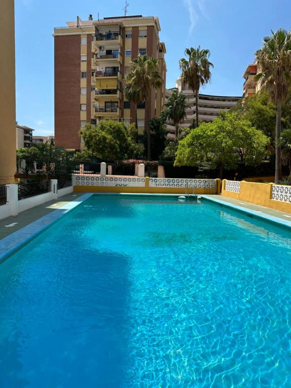 una gran piscina azul con un edificio alto en el fondo en Apartamento moderno Centro de Marbella, en Marbella