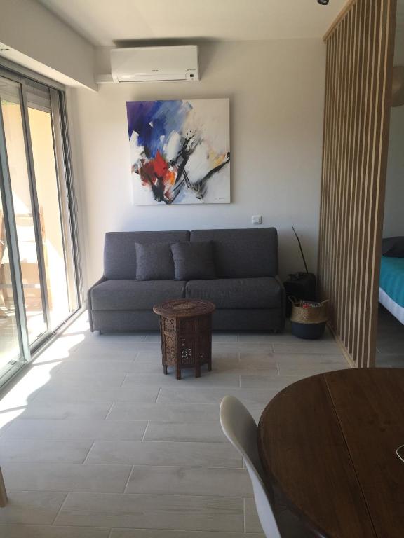 a living room with a couch and a table at Marco Polo 3 pers pool in Mandelieu-La Napoule