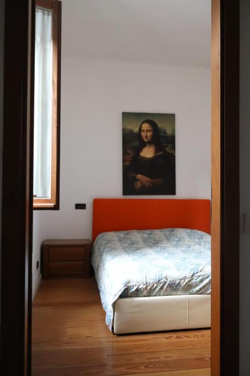 1 dormitorio con 1 cama de color naranja y una pintura en la pared en Nottetempo, en Desio