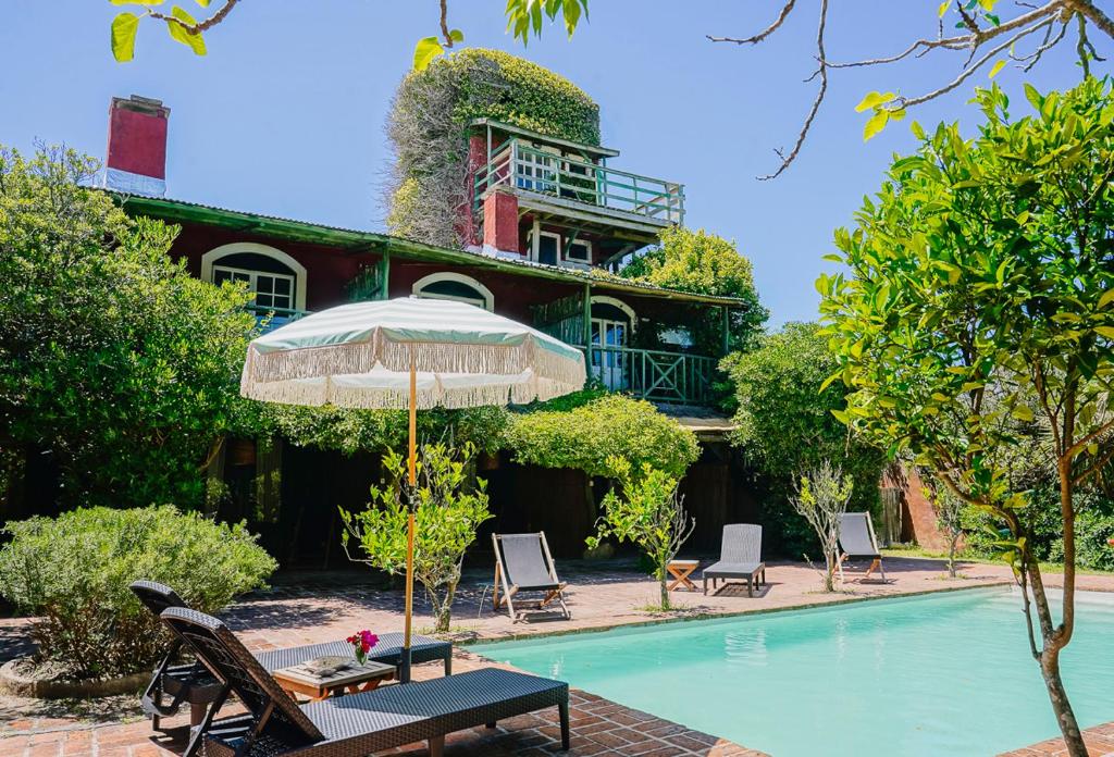 Posada Paradiso في خوسيه اجناسيو: مسبح فيه مظله وكراسي ومنزل