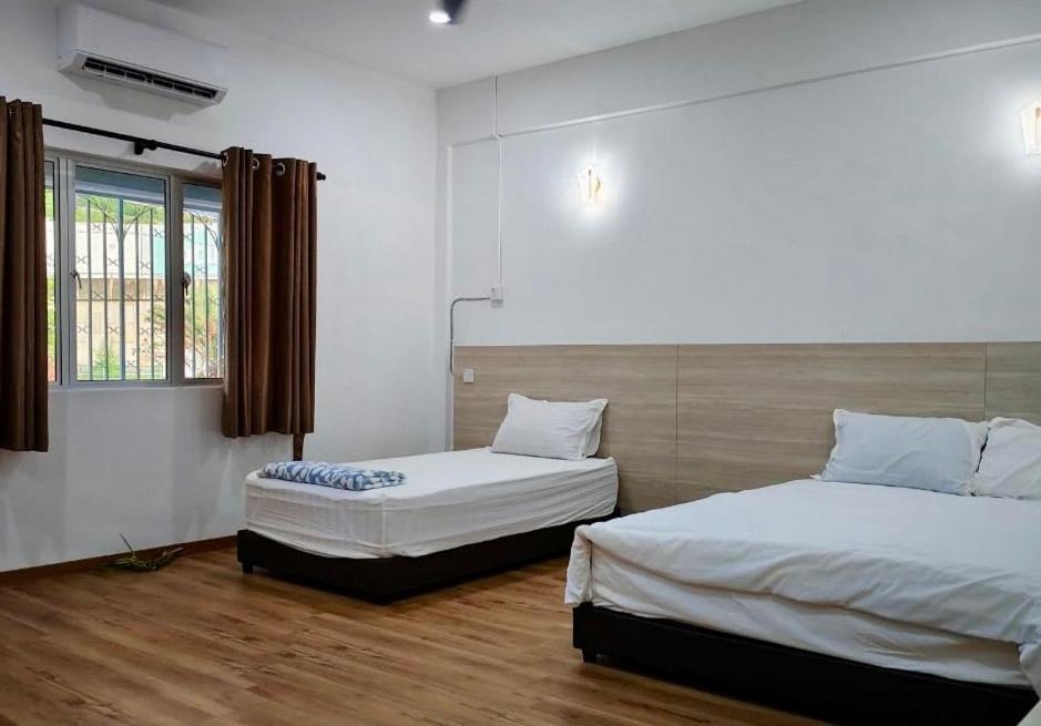 a bedroom with two beds and a window at Grace Homestay Taiping in Taiping