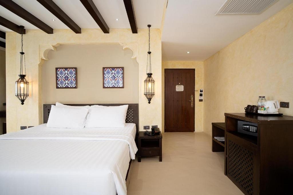 A bedroom view showing the bed, entry door, minibar cabinet and room controls.