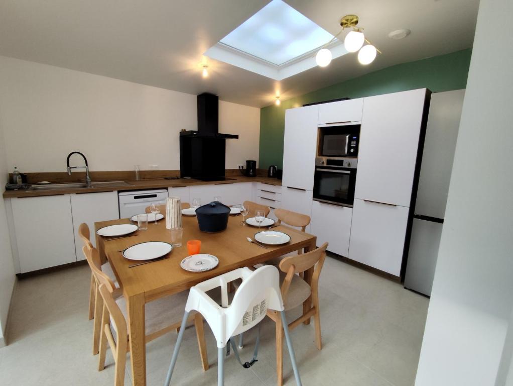 eine Küche mit einem Holztisch und weißen Schränken in der Unterkunft L'ancienne Poste in Fort-Mahon-Plage