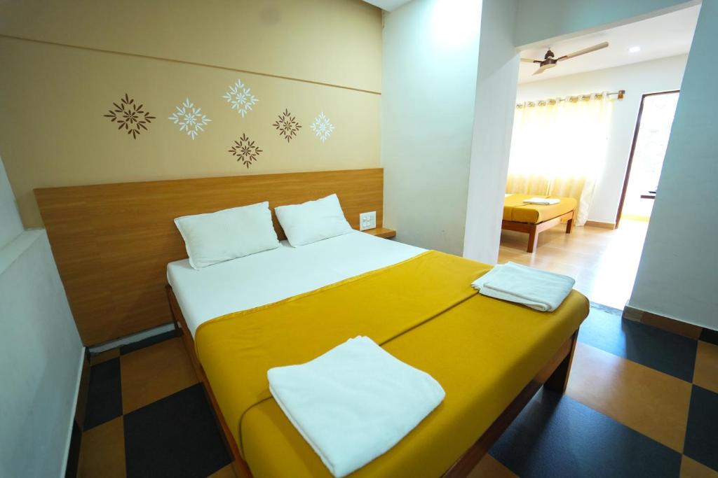 迈索尔Nandan Residency的一间卧室配有黄色的床和2个白色枕头