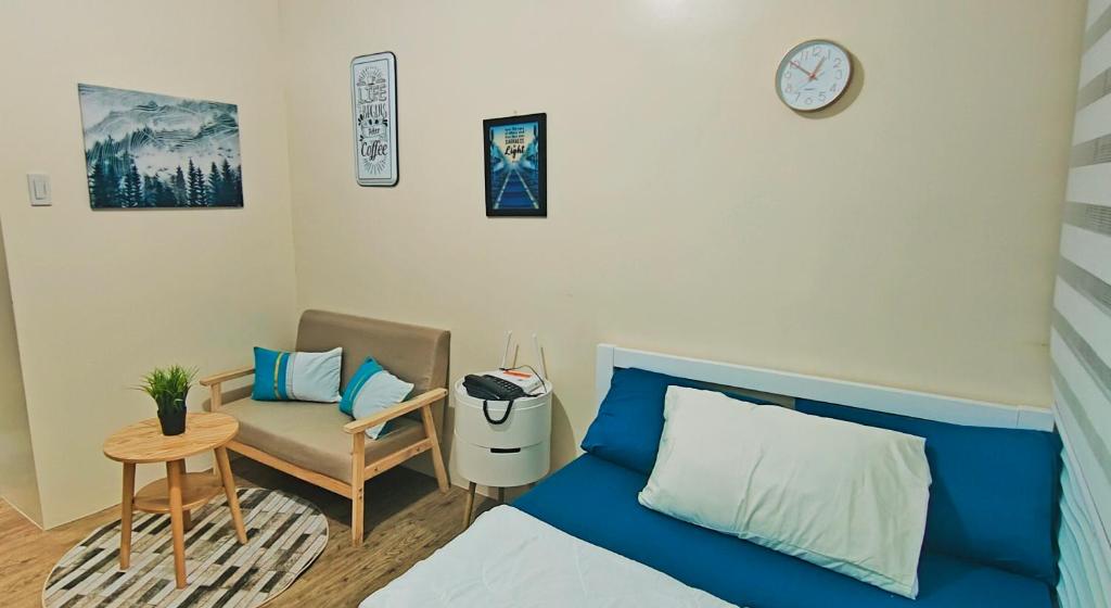 a bedroom with a bed and a chair and a clock at Condo in Silang near Nuvali - Dy's Haven Suites in Silang