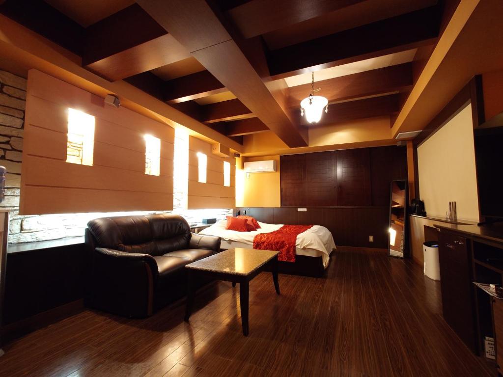 a bedroom with a bed and a couch and a table at ホテル カーシュ Cache 男塾ホテルグループ in Himeji