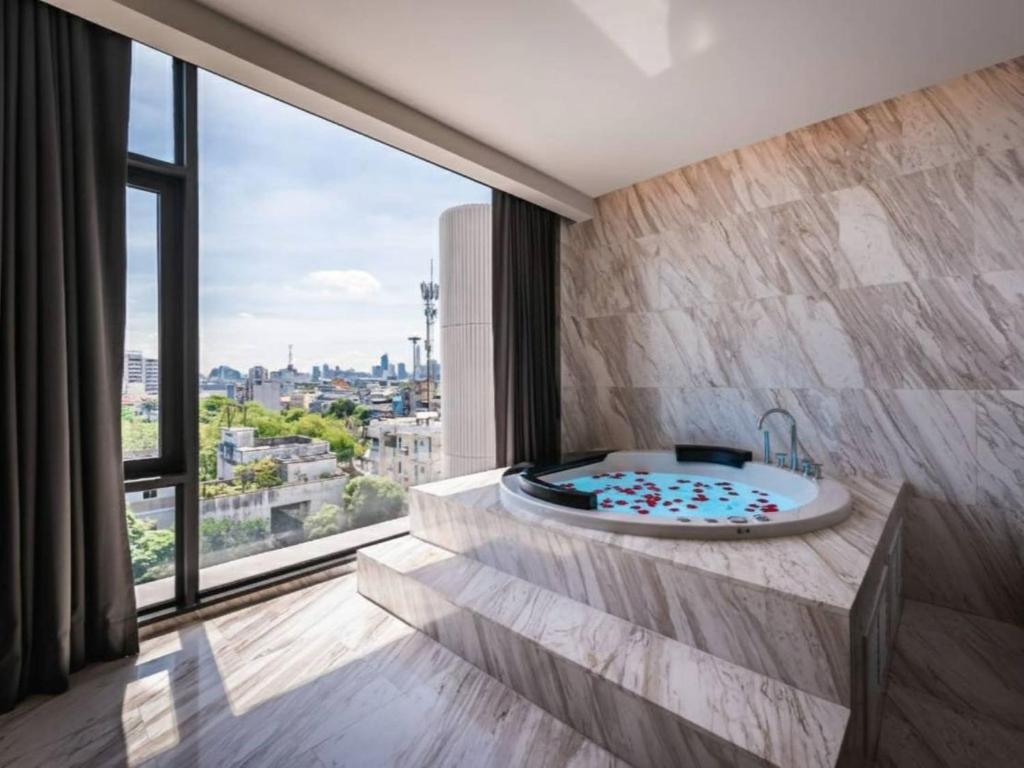 A marble bathroom with a raised whirlpool tub beside a large city-facing window.
