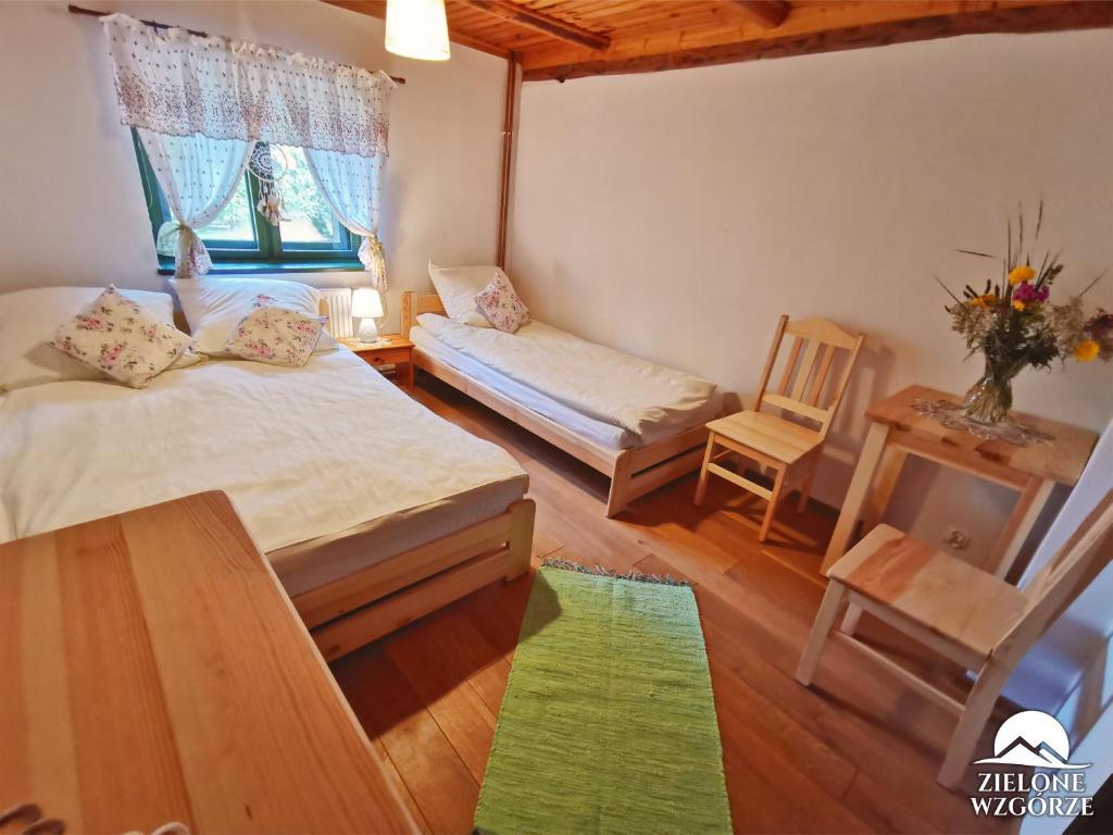a bedroom with two beds and a table and a chair at Zielone Wzgórze in Lasowka