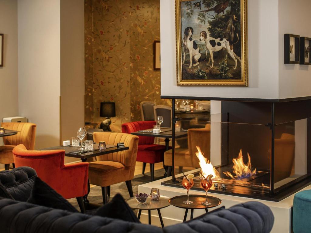 Mercure Rambouillet Relays Du Château في رامبوييه: مطعم فيه موقد وطاولات وكراسي