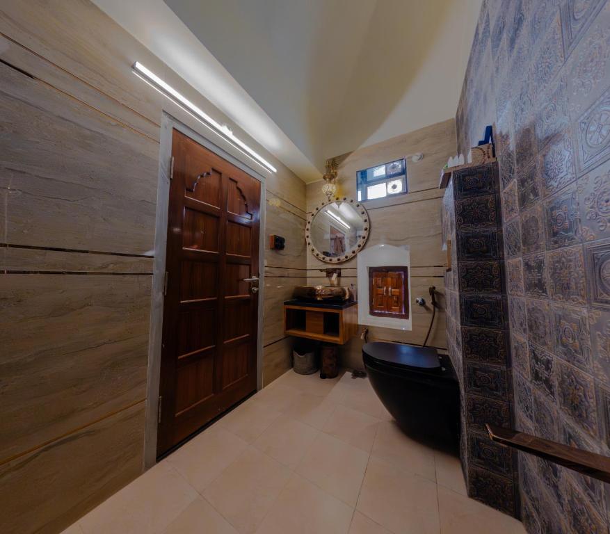 ein Badezimmer mit Toilette und Holztür in der Unterkunft Jeevan Haveli Heritage Hotel & Museum in Nawalgarh