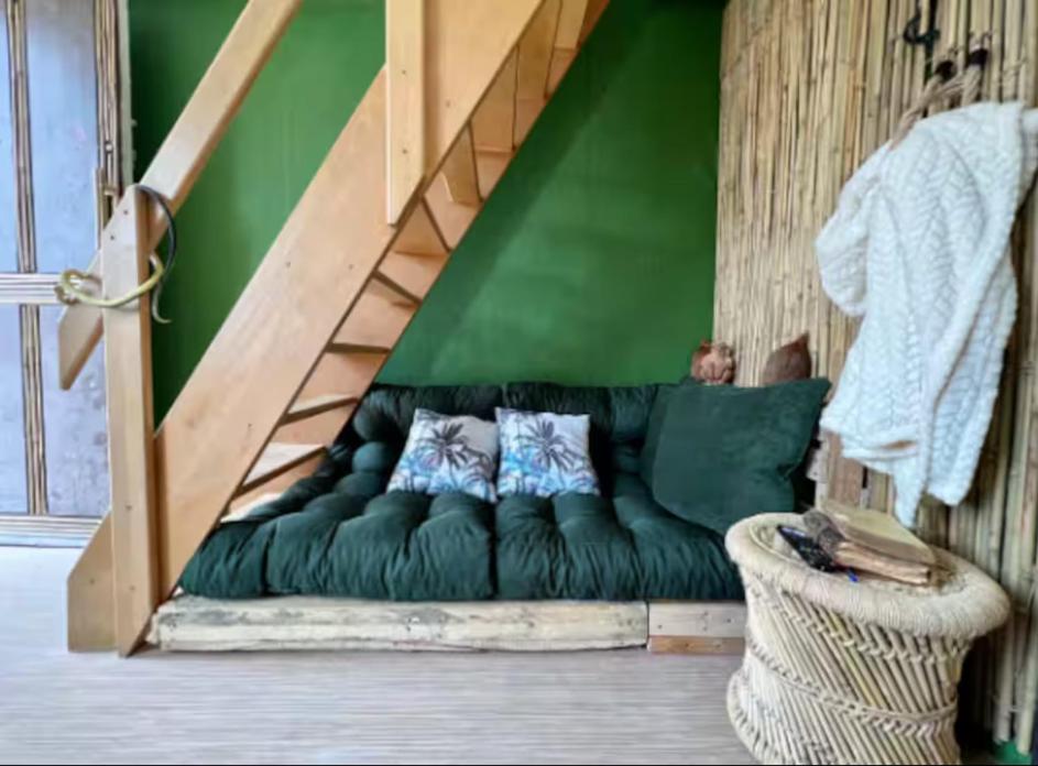 eine grüne Couch mit Kissen darauf in einem Zimmer in der Unterkunft Love room Évasion tropicale in Souppes-sur-Loing