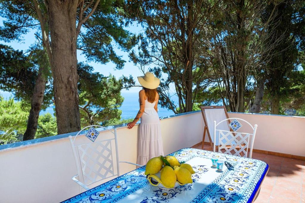 卡普里Casa Schiattarella Capri的站在阳台上戴帽子的女人