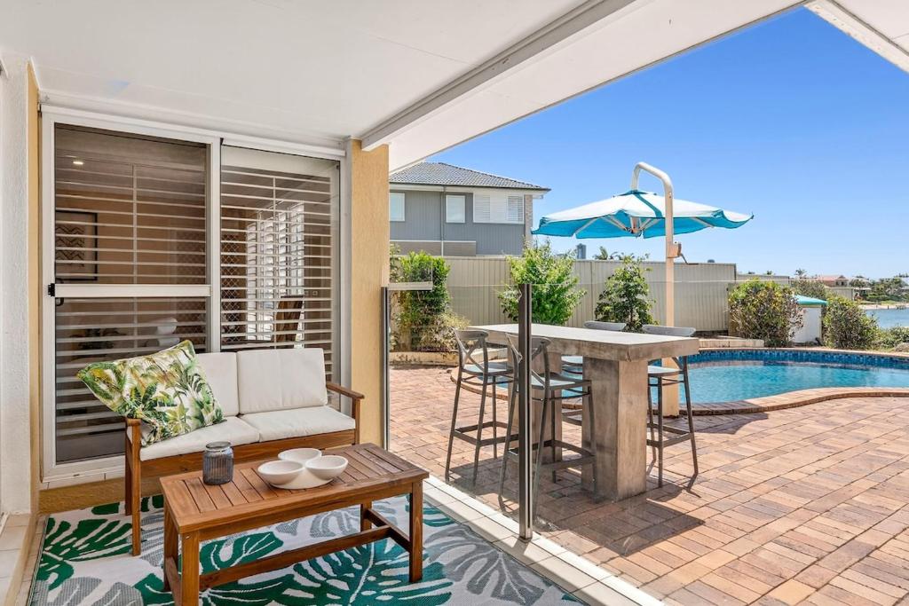 een patio met een bank, een tafel en een zwembad bij Waterfront entertainers dream with private beach in Gold Coast