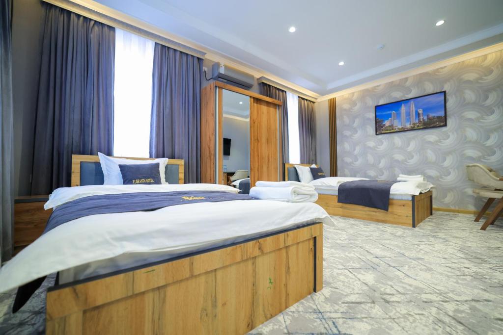 a hotel room with two beds and a tv at Floranta Hotel in Qarshi