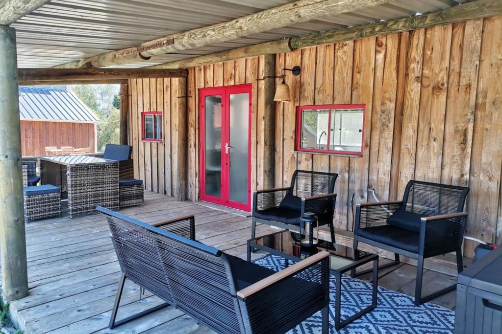 a deck with chairs and a red door at Le Chalet du Lâcher-Prise in Éguzon-Chantôme