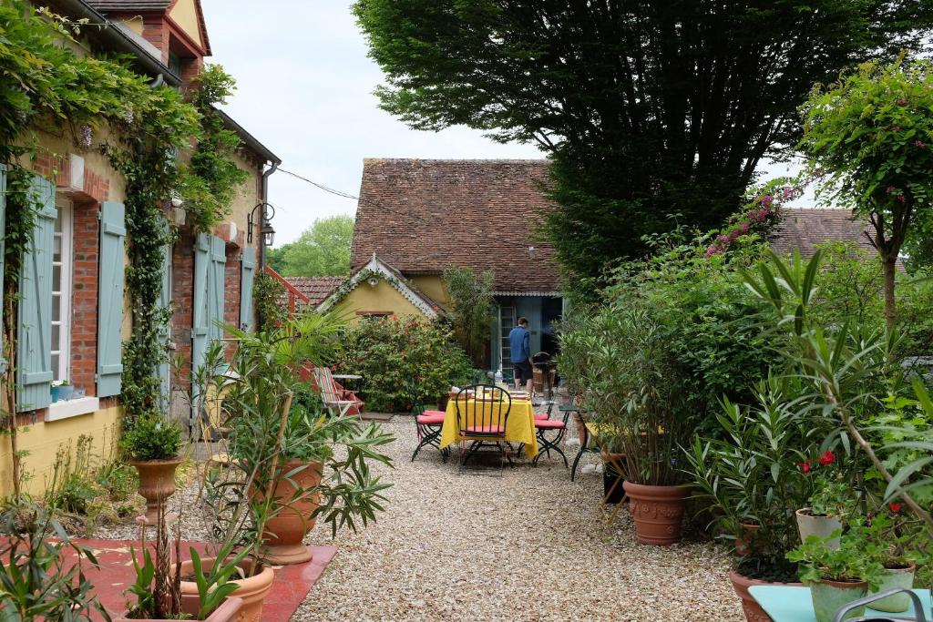 un jardín con mesa, sillas y plantas en Chambre 3, Le clos du Ru, en Presnoy