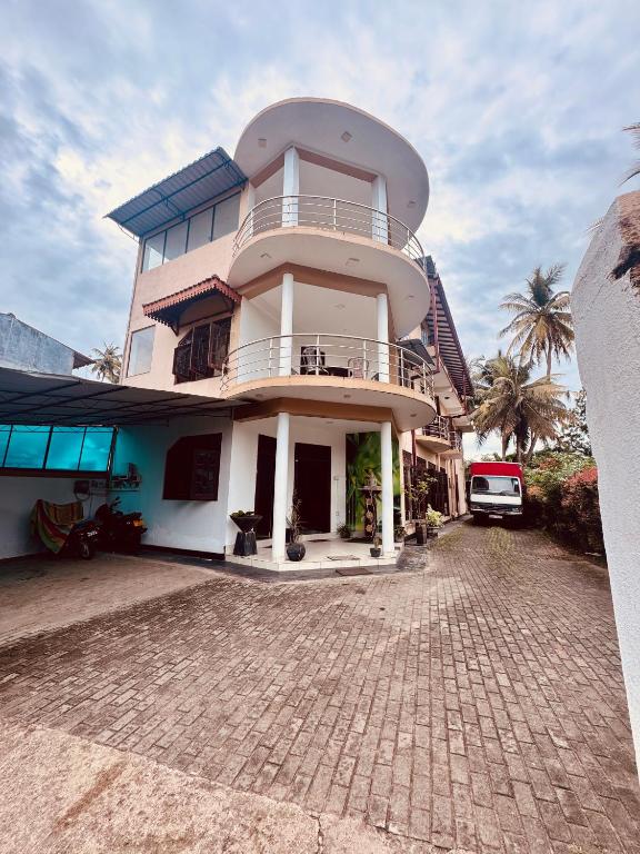 a large white building with a balcony on a street at Harshi Guest House in Matara