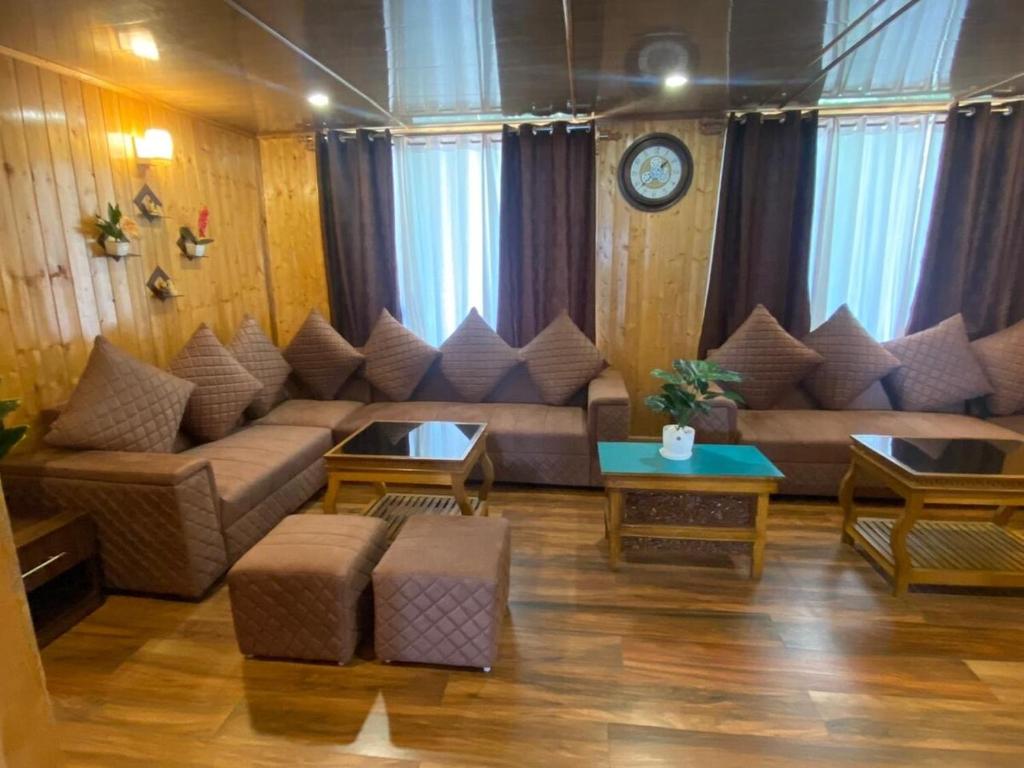 a living room with couches and tables and a clock at DreamVilla Retreat Apartment Pelling in Pelling