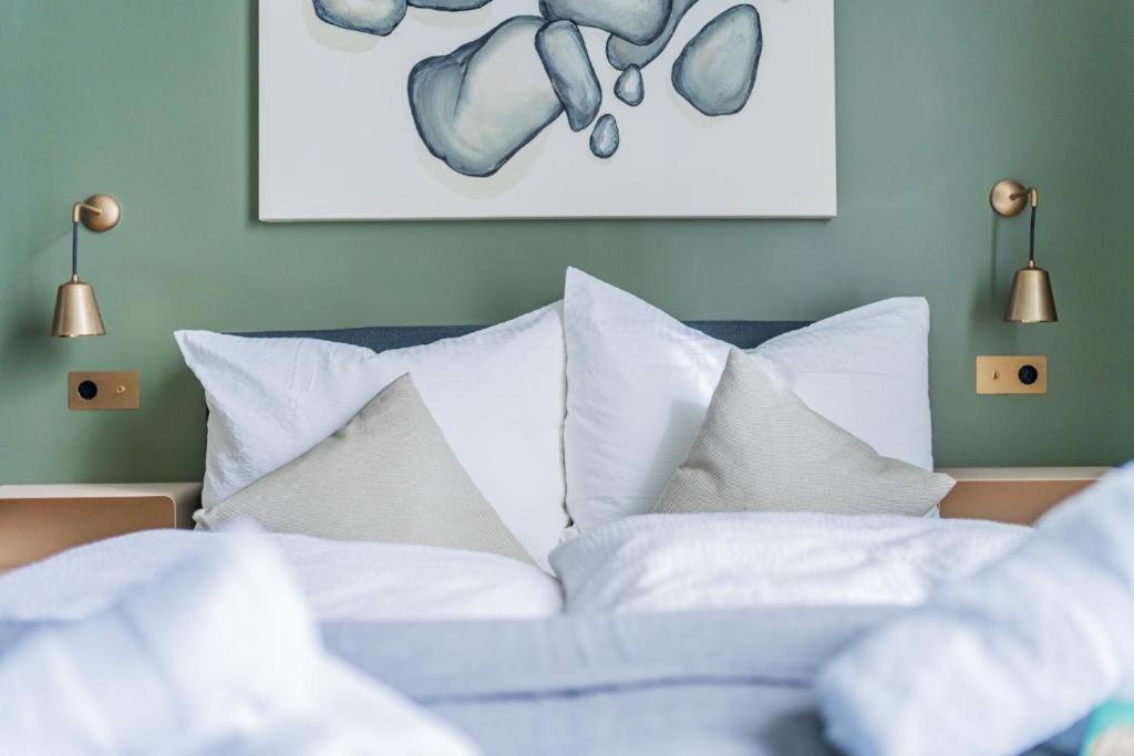 een bed met witte kussens en een schilderij aan de muur bij HOME1 - Belvedere Boutique Hostel in Wenen
