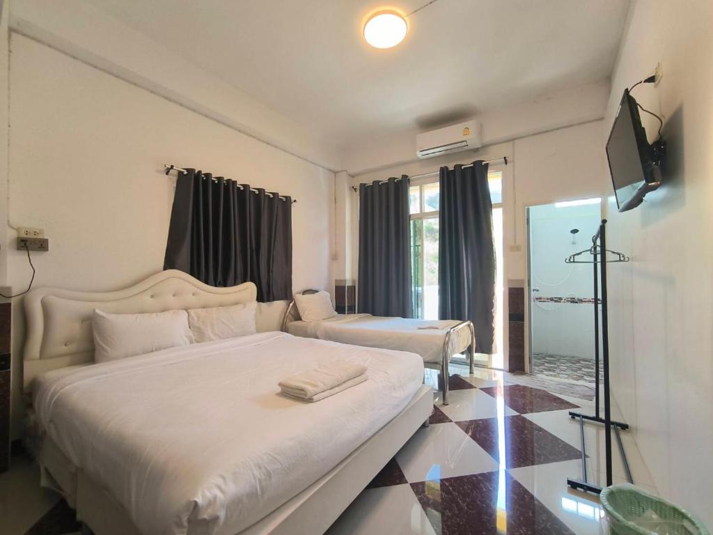 a hotel room with two beds and a television at SB Betong GUESTHOUSE in Betong