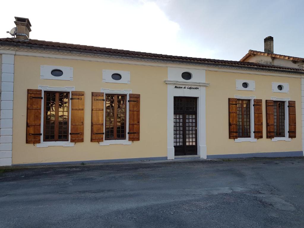 a yellow building with windows and doors on a street at Maison De Lafenestre in Saint-Maigrin
