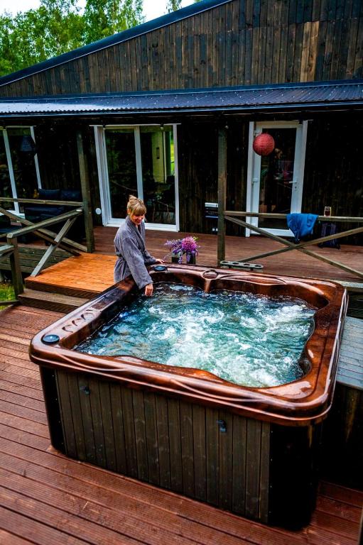 a man standing in a large tub on a deck at HOLIDAY CABIN 'CRANE' with a private hot-tub and sauna extra fee in Avotkalni
