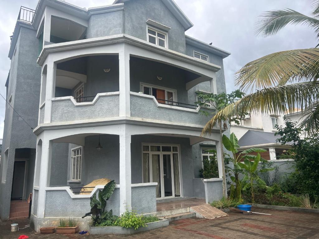 a gray house with a balcony and a palm tree at Coconut House in Albion