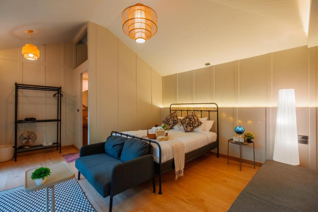 a bedroom with a bed and a blue couch at เดอะริเวอร์ แม่กำปอง The River Maekampong Chiang Mai in Ban Pok Nai