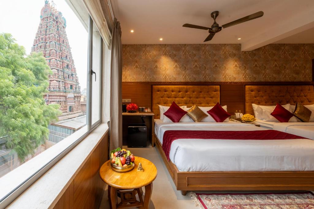 a bedroom with a bed and a large window at Gopuram Grand in Madurai