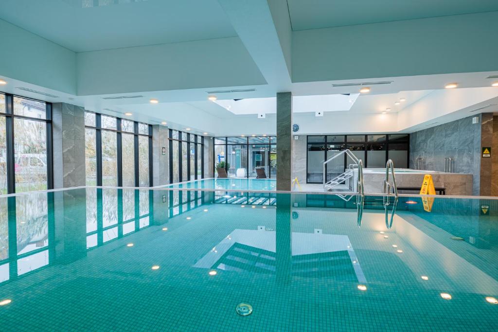 an indoor swimming pool with a large window and a swimming poolasteryasteryasteryastery at APT Nadmorskie - GreenPort z basenem i strefą SPA in Kołobrzeg