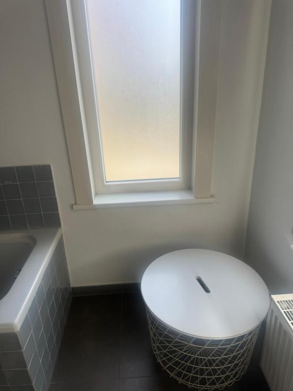 a bathroom with a white toilet and a window at Woning in Damme nabij Brugge in Damme
